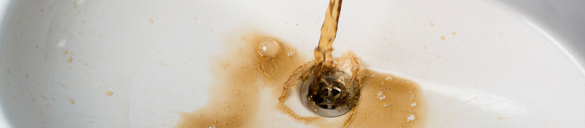 Brown Water Runs Into a White Sink