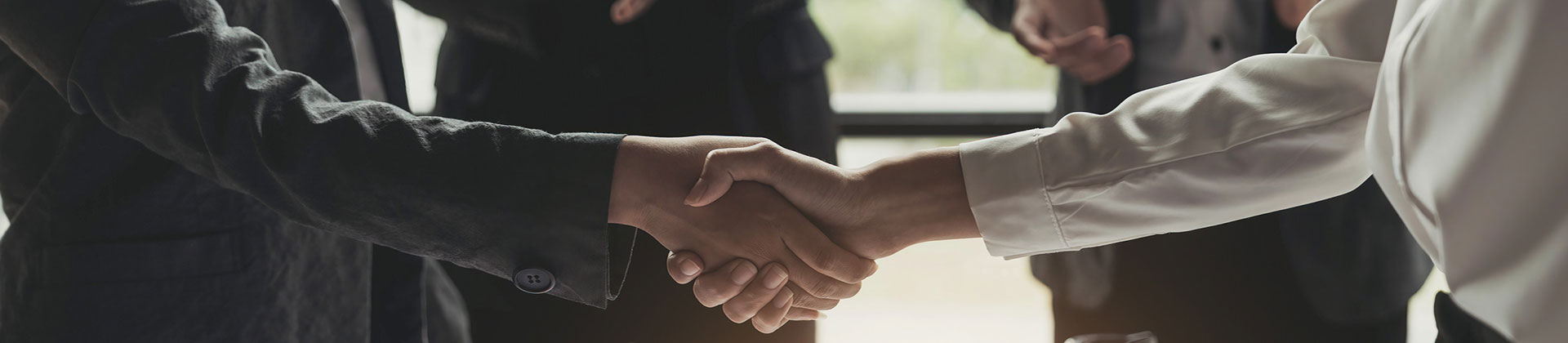 People Shaking Hands Over Office Desk as Others Applaud